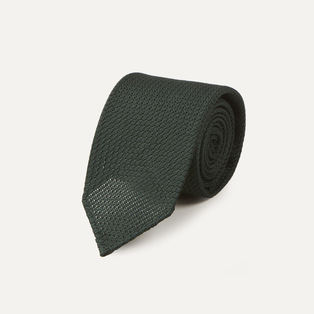 Green large knot Grenadine handrolled tie by Drake's, showcasing its textured fabric and classic knot on a neutral background.