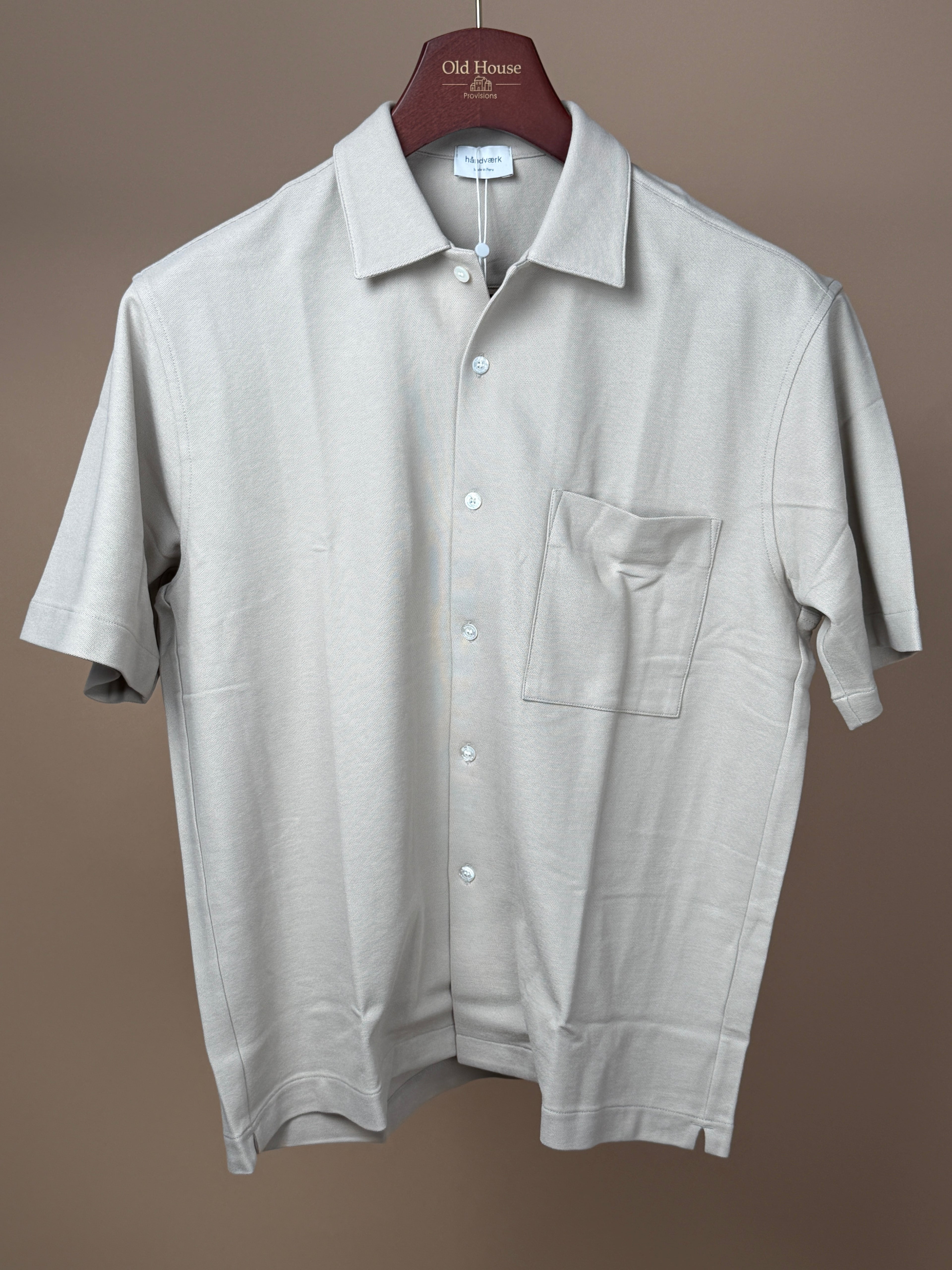 Håndværk foam pique button-up short sleeve shirt displayed on a hanger, showcasing its casual, textured fabric and classic fit.