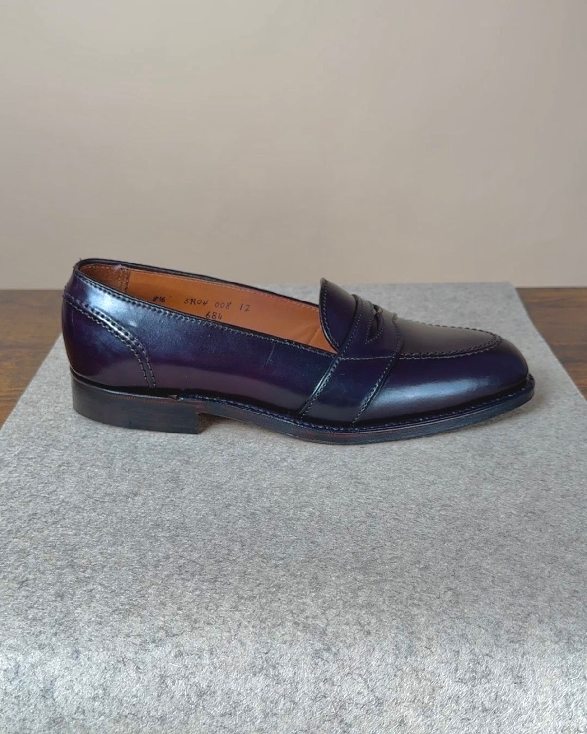 Alden full strap penny loafer in Color 8 Shell Cordovan showing smooth leather upper and classic design on a wooden surface.