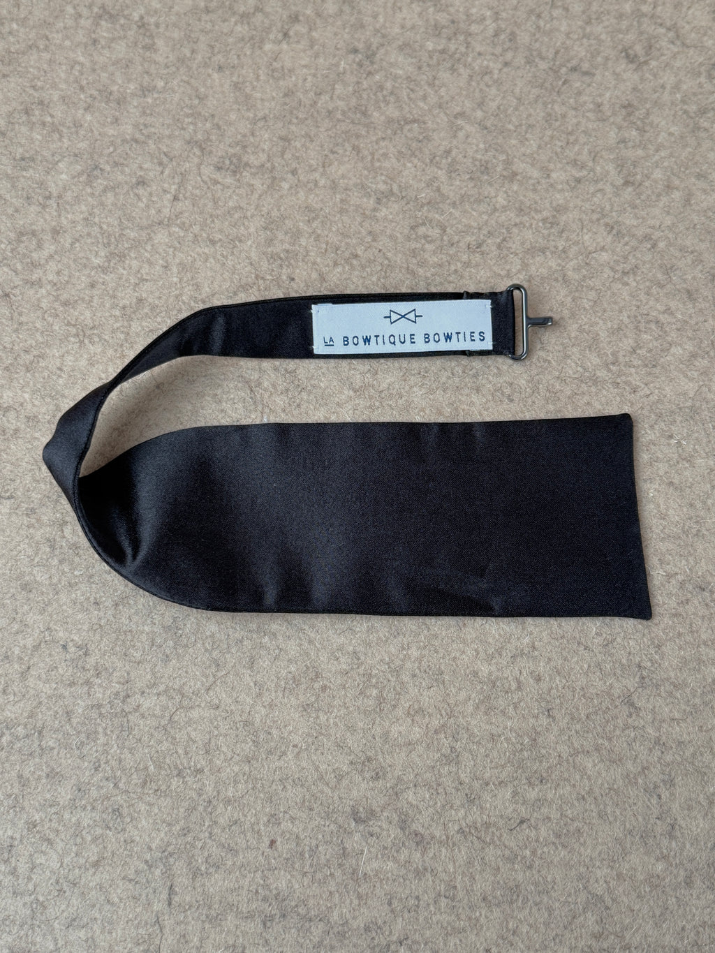 Black silk satin medium batwing bow tie from La Bowtique, showcasing its elegant, smooth fabric and classic shape.