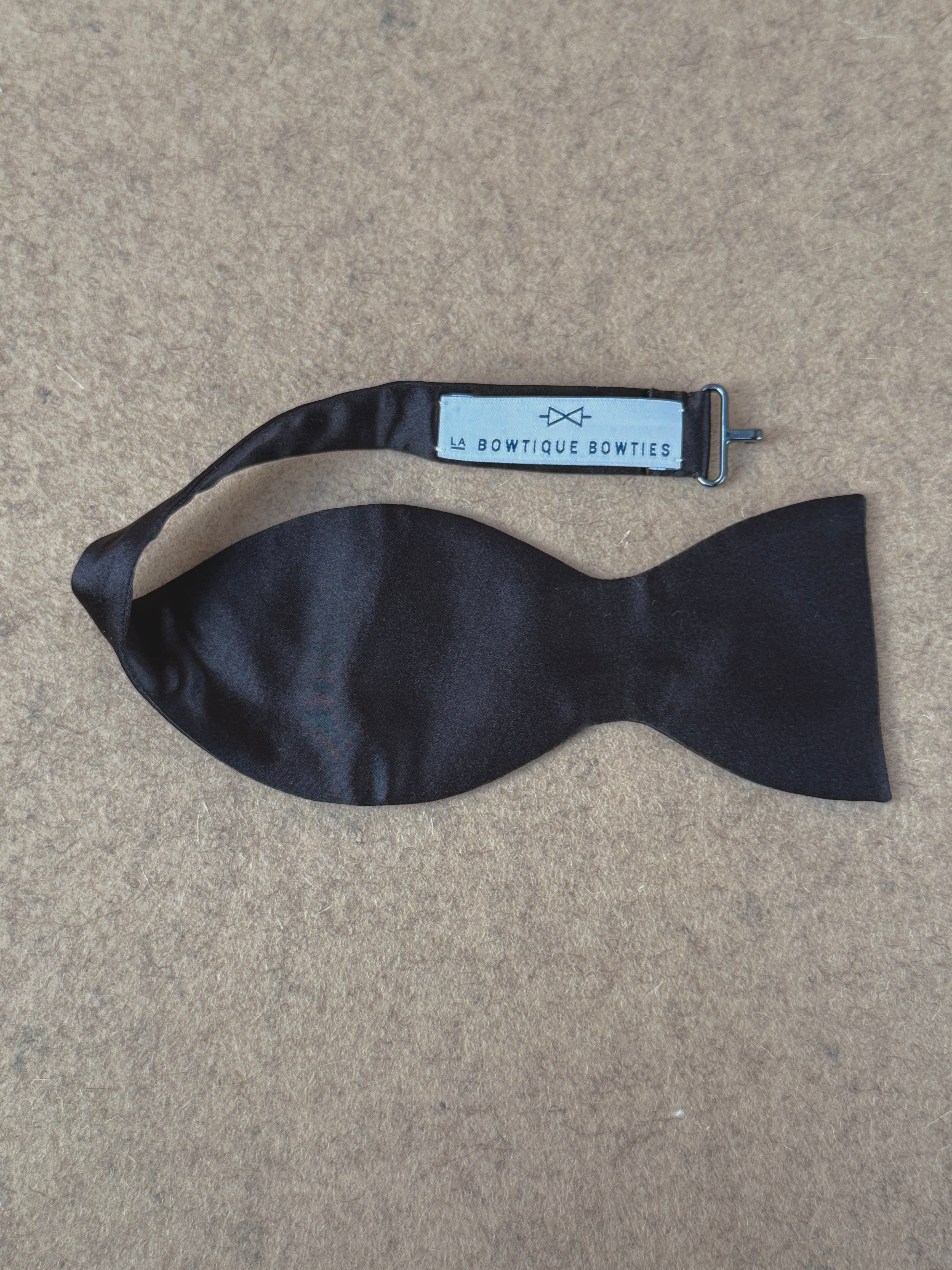 Black silk satin medium classic bow tie from La Bowtique, showcasing its elegant knot and smooth fabric texture.