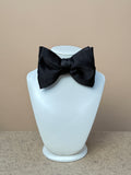 Black silk satin medium dropped bow tie by La Bowtique, showcasing its elegant design and smooth satin finish.