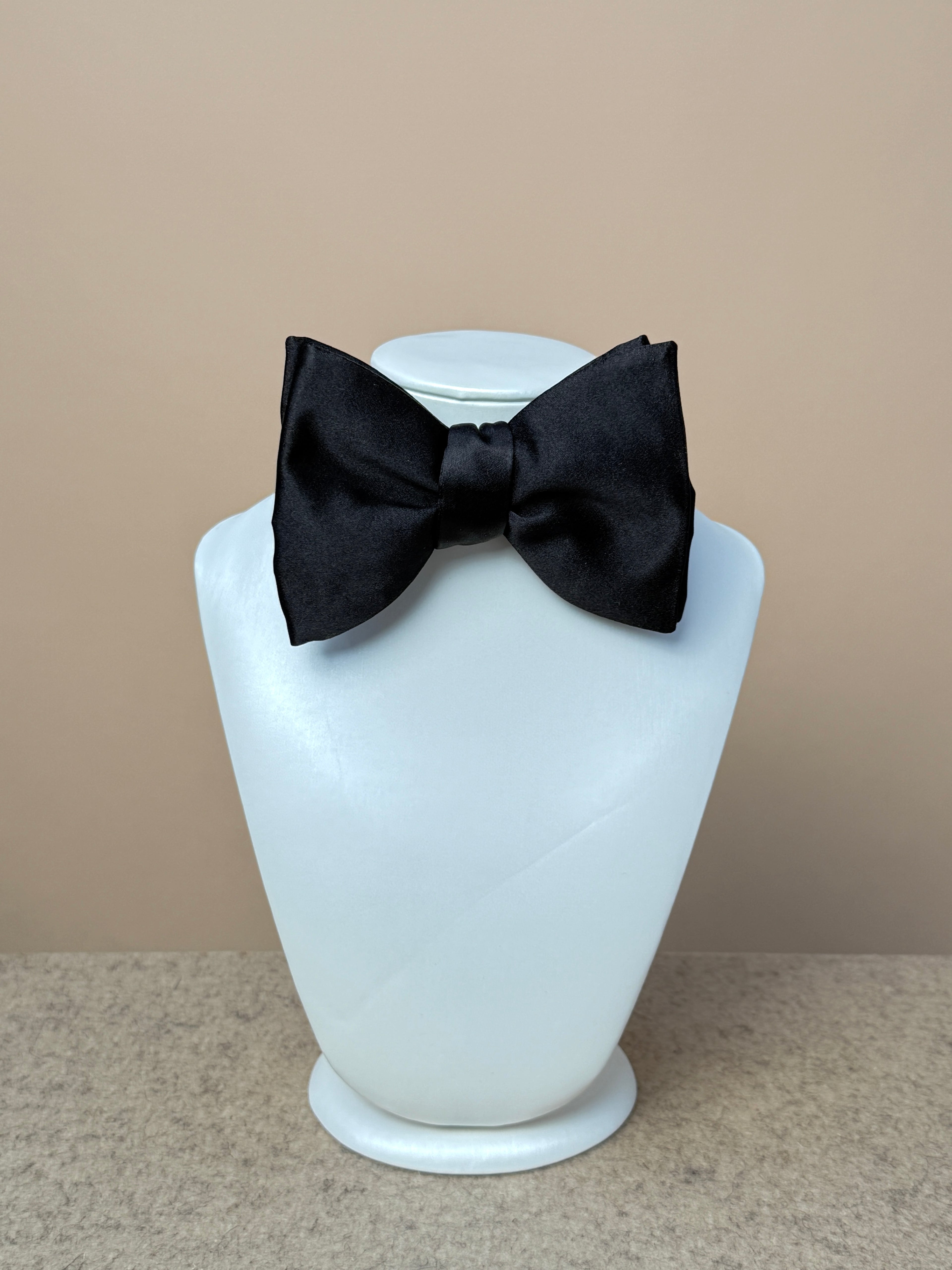 Black silk satin medium dropped bow tie by La Bowtique, showcasing its elegant design and smooth satin finish.