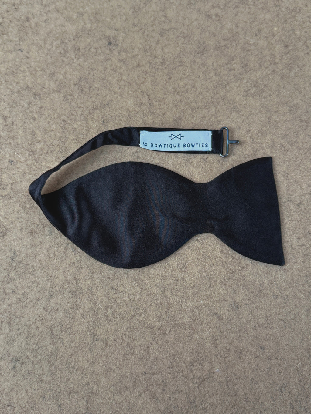 Black silk satin Crompton medium dropped bow tie from La Bowtique, showcasing its elegant and stylish accessory design.