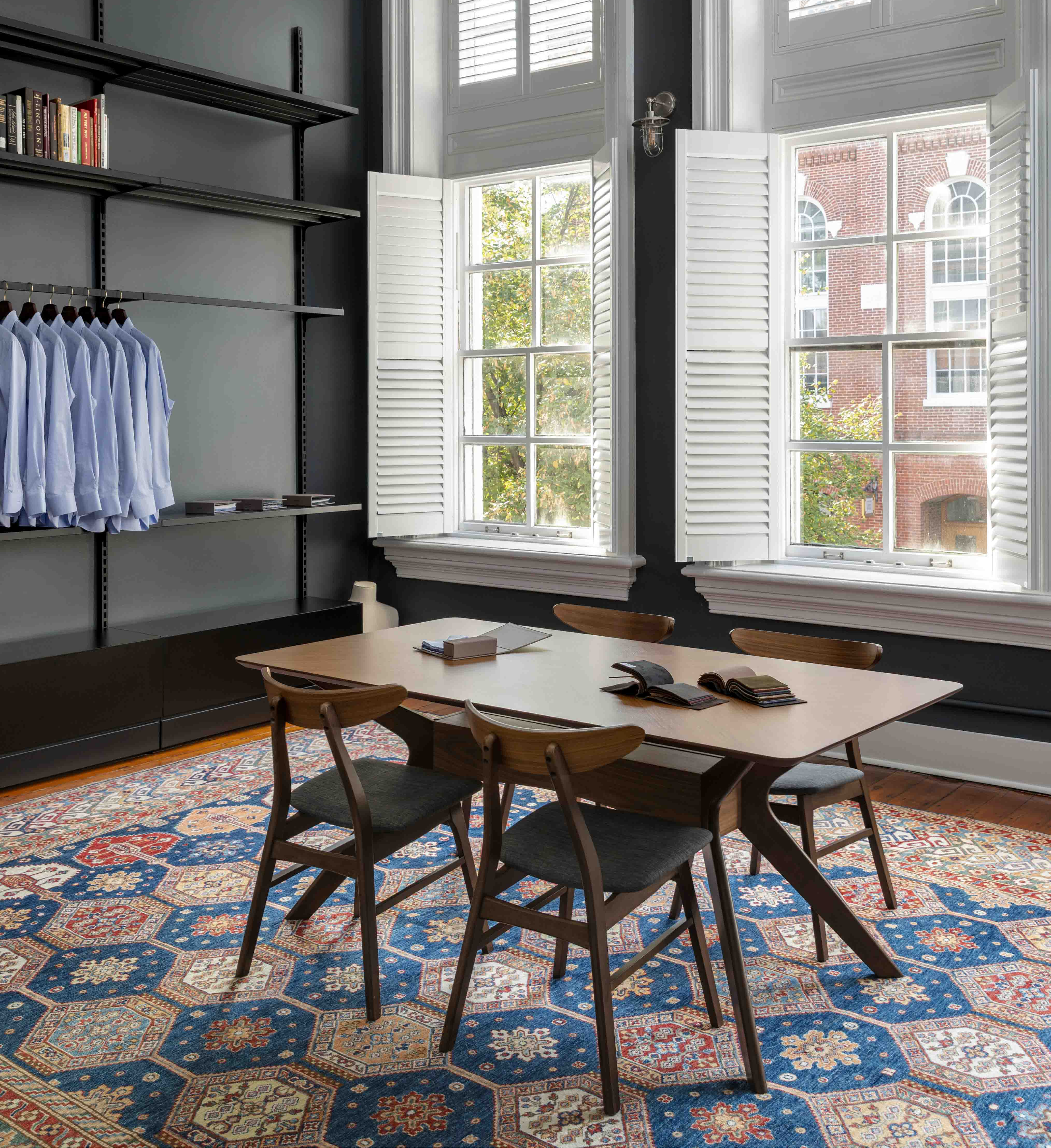 Modern interior with a dining table and chairs in a room with high ceilings and large windows.