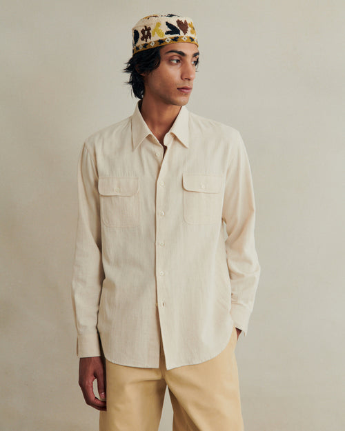 Undyed artist shirt by De Bonne Facture in cotton hemp gabardine, displayed on a hanger with a natural fabric texture.