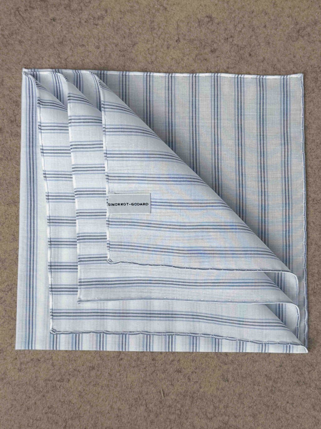Simonnot-Godard Archive striped cotton pocket square in white, blue, and navy with classic pattern and folded design.