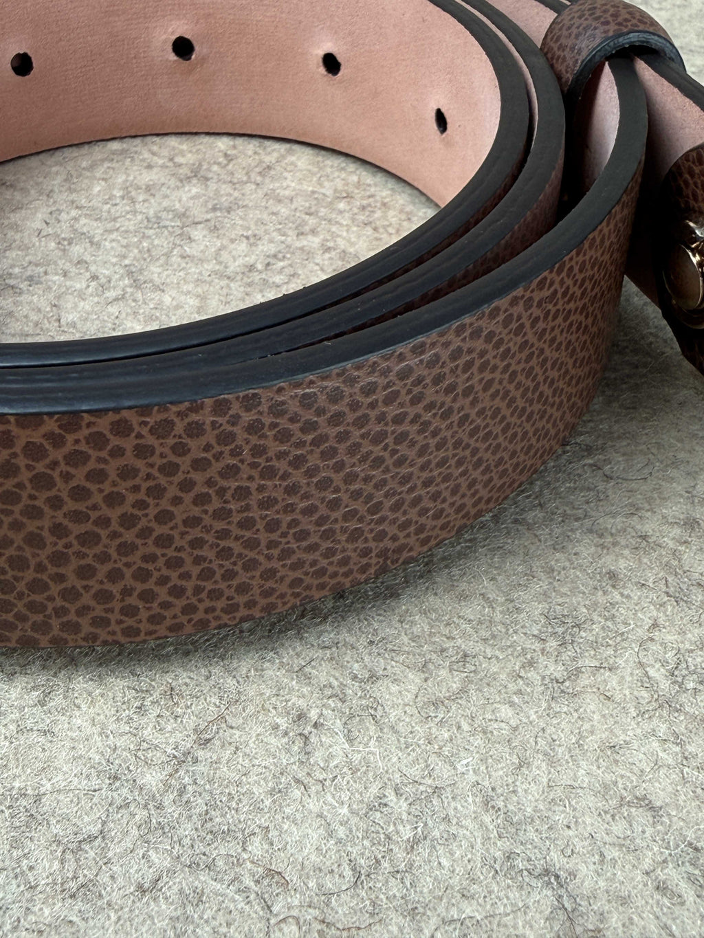 Brown pebble grain spur belt by Simonnot-Godard, showcasing textured leather and classic buckle detail.