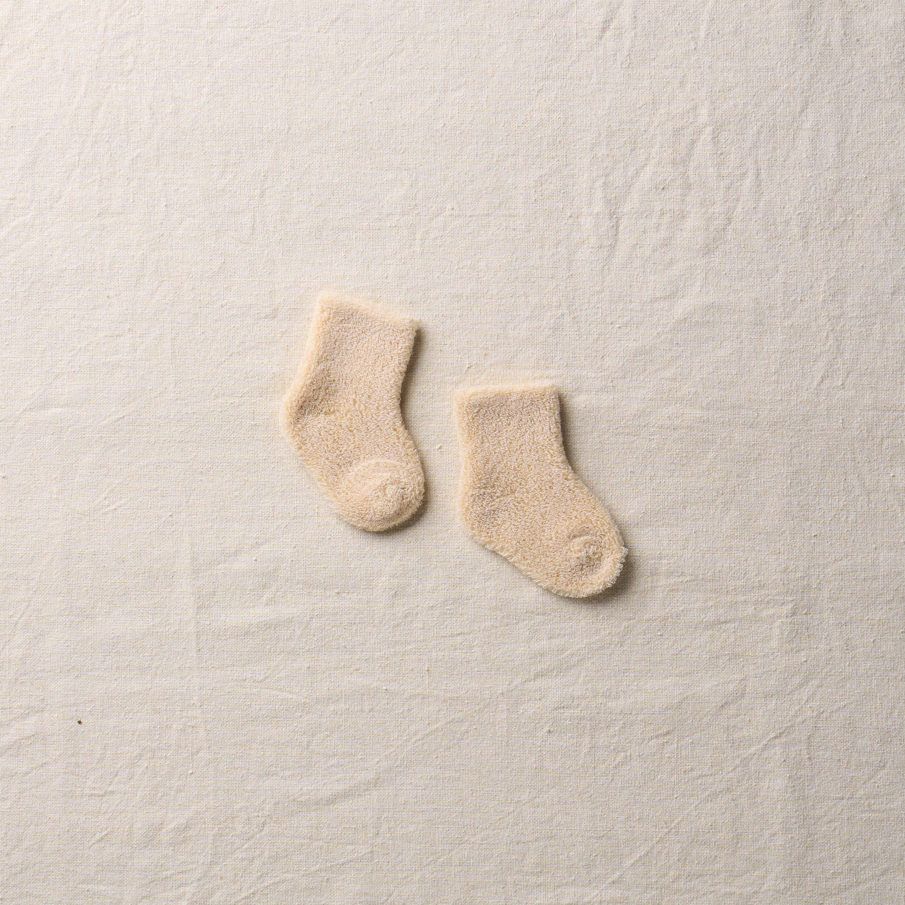 Pair of beige socks on a textured beige surface
